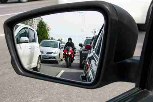 View of motorcycle in car side mirror, concept of motorcycle accident lawyer in Decatur