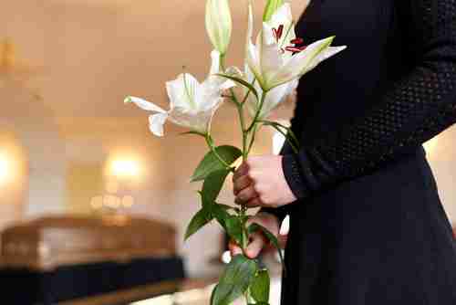 Druid Hills wrongful death lawyer concept, woman holding lilies at funeral
