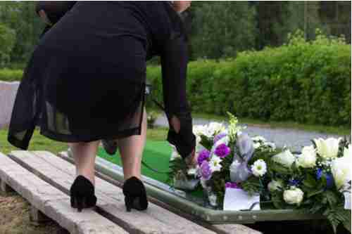 Concept of Scottdale wrongful death lawyer, woman placing flowers on grave