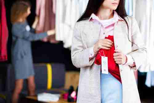 Young woman shoplifting clothes