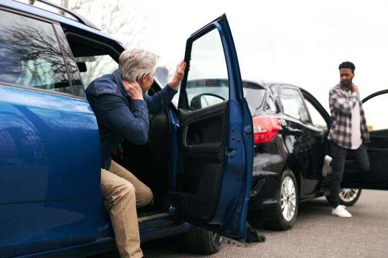 Image is of an older man getting out of his car while holding his neck and a younger man getting out of another car while holding neck after the two were involved in a car accident. Concept of how comparative negligence can affect your personal injury claim in Georgia
