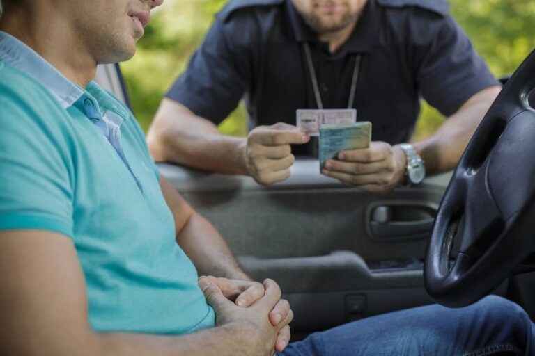 Image is of a young male driver being pulled over and questioned by a police officer, concept of how to reinstate a driver's license after a DUI in Georgia
