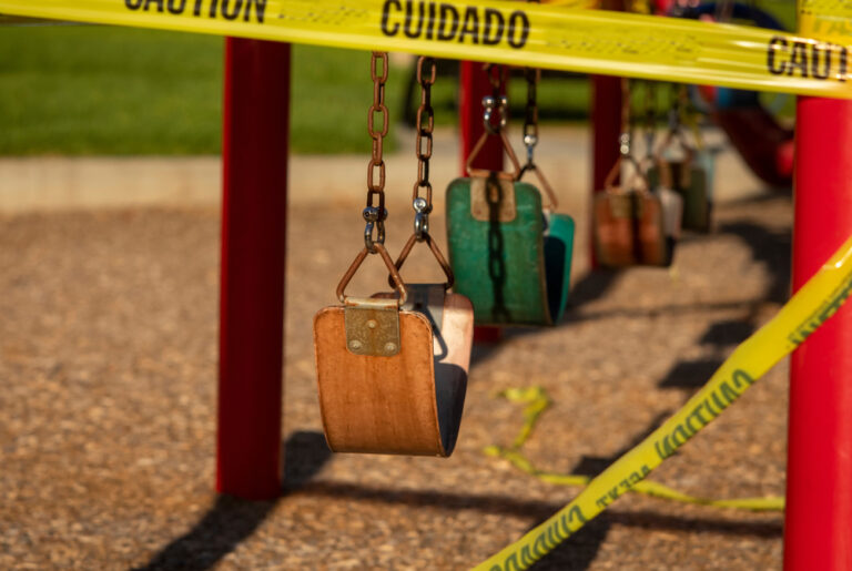 Image is of a swing set that is taped off with yellow caution tape, concept of premises liability and children injuries.