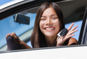Image is of a teen driver holding car keys and smiling while sitting in driver's seat, concept of how parents can help prevent underage dui